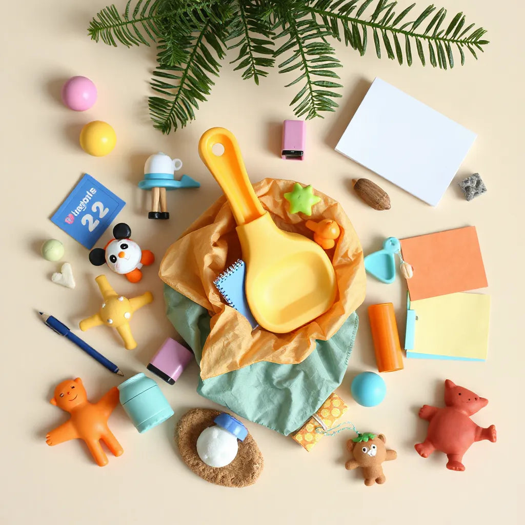 Small toys and stationery items arranged around a scoop-shaped container on a tidy background